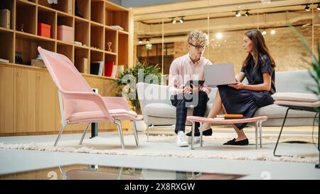 Portrait of Two Creative Colleagues Collaborating and Pointing at the Laptop in Modern Office. Female Manager Consults White Project Manager, They Brainstorm on the Project Stock Photo