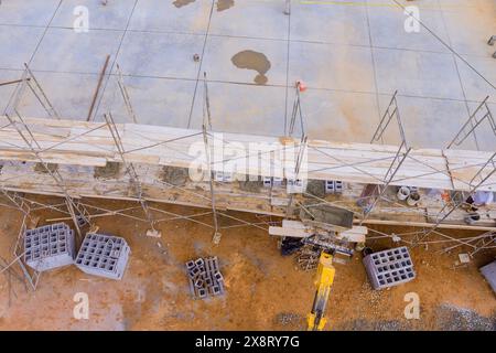 Masonry worker stands on scaffolding while making concrete wall using cement blocks Stock Photo