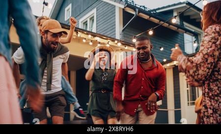 Diverse Multicultural Friends and Family Dancing Together at an Outdoors Garden Party Celebration. Young and Senior People Having Fun on a Perfect Summer Afternoon. Stock Photo