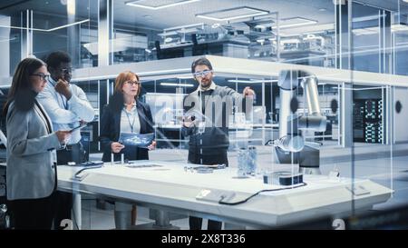 Robotics Engineers, Project Manager and Machinery Operator Collaborate on a Robot Arm Project, Standing with Tablet Computers in Scientific Technology Lab. Team Developing an AI Robotic Arm. Stock Photo