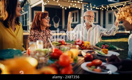 Portrait of a Grandfather Celebrating His Grandson Achievements, Praising a Young Man at a Family Barbecue Gathering with Friends and Relatives. Multicultural People Chatting and Having Fun. Stock Photo