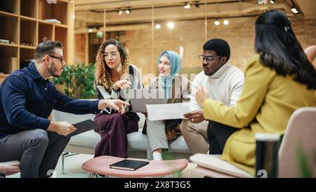 Multiethnic Group of People Use Tablet, Laptop and Statistics Data to Discuss Work in Office Conference Meeting Room. Diverse Colleagues Solving Problems, Teamwork leads to Great Result Stock Photo