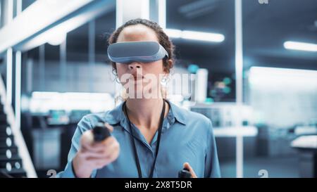 Portrait of a Female Engineer Using a Virtual Reality Headset with Controllers to Operatean Indsutrial Robot or Spend Time in Virtual Office Metaverse. Stock Photo