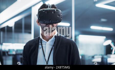 Portrait of a Young Industrial Specialist Wearing a Virtual Reality Headset in a High Tech Industrial Laboratory Facility. Factory 4 Concept and Metaverse Virtual Office Space. Stock Photo