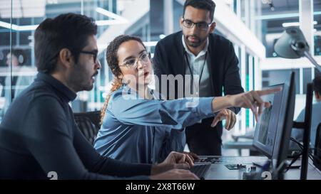 Team of Industrial Design Agency Specialists Discussing a 3D Circuit Board Model Created on a CAD Software on Desktop Computer. Young Men and Female Working in Electronics Development Factory. Stock Photo