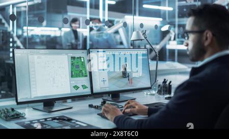 Portrait of a Young Hispanic Industrial Engineer Developing 3D Model of a Circuit Motherboard on Computer CAD Software in a Factory. Modern Technological Research and Development Center. Stock Photo
