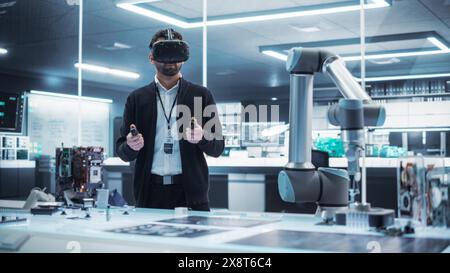 Portrait of a Young Specialist Using a Virtual Reality Headset with Controllers to Operate an Experimental Robotic Arm Machine. High Tech Industrial Laboratory Facility. Stock Photo