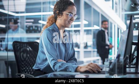 Portrait of a Beautiful Smiling Smart Industrial Engineer Working on a 3D Circuit Motherboard Project on Computer CAD Software in an Agency. Modern Technological Research and Development Office. Stock Photo