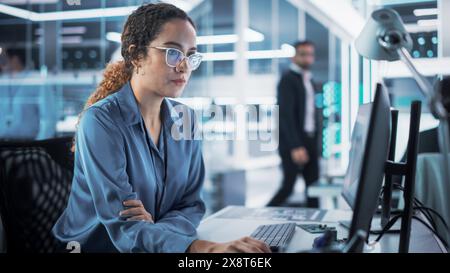 Focused Multiethnic Female Industrial Engineer Developing 3D Model of a Circuit Motherboard on Computer CAD Software in a Startup Facility. Modern Technological Research and Development Center. Stock Photo