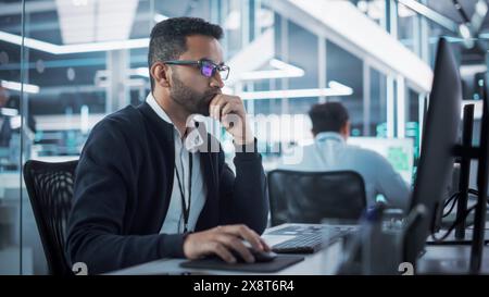 Portrait of Multiethnic Industrial Engineer Developing 3D Model of a Circuit Motherboard on Computer CAD Software in a Factory. Modern Technological Research and Development Center. Stock Photo