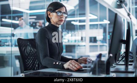 Adult Female Industrial Engineer Developing 3D Model of a Circuit Motherboard on Computer CAD Software in a Startup Facility. Modern Technological Research and Development Center. Stock Photo
