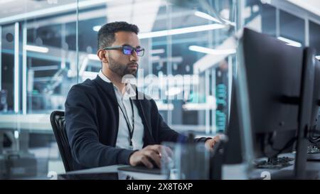 Portrait of Multiethnic Industrial Engineer Developing 3D Model of a Circuit Motherboard on Computer CAD Software in a Factory. Modern Technological Research and Development Center. Stock Photo