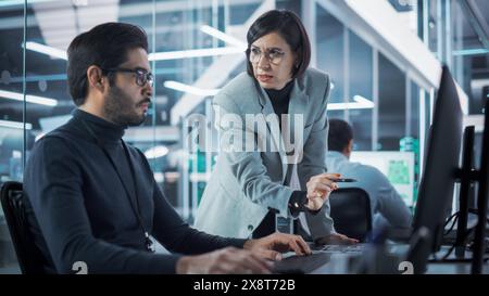 Two Industrial Design Agency Specialists Discussing a 3D Circuit Board Model Created on a CAD Software on Desktop Computer. Young Man and Female Working in Electronics Development Factory. Stock Photo