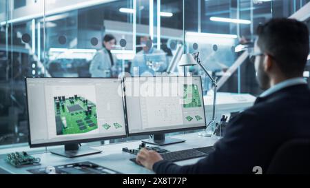 Portrait of a Young Hispanic Industrial Engineer Developing 3D Model of a Circuit Motherboard on Computer CAD Software in a Factory. Modern Technological Research and Development Center. Stock Photo