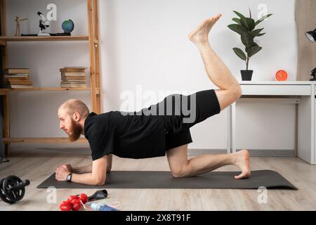 Exercising at home. An athlete doing sports exercises lying on the floor and lifting his legs up. Sports and lifestyle concept Stock Photo