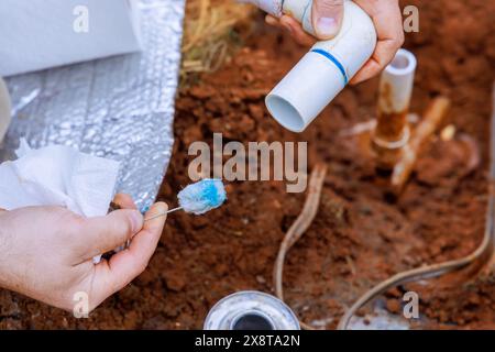 During course of repair work, technician plumber uses clear primer for PVC pipe with before gluing it together Stock Photo