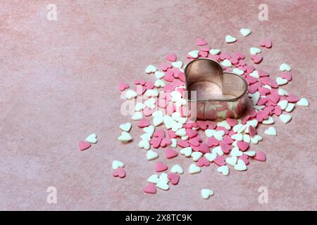 Heart-shaped cookie cutter and sugar hearts on a pink background Stock Photo