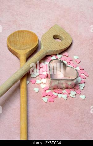 Cooking spoon and heart-shaped cookie cutter with sugar hearts Stock Photo