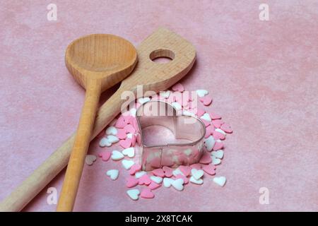 Cooking spoon and heart-shaped cookie cutter with sugar hearts Stock Photo