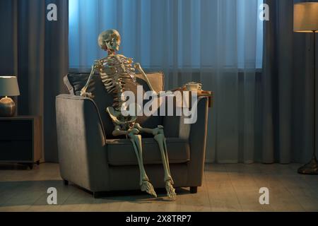 Waiting concept. Human skeleton sitting in armchair indoors Stock Photo