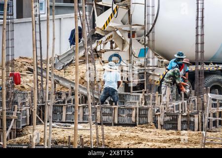 Concrete pouring from cement mixers truck while construction worker laying concrete to the floors beams of building Stock Photo