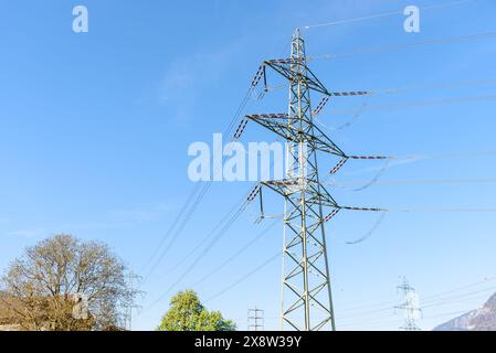 Low angle view of a tall electricity pylon supporting high voltage lines in the mountains on a clear spring day Stock Photo