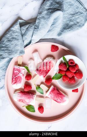 Refreshing homemade raspberry popsicles on tray with ice and berries Stock Photo