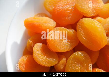 Dried fruits. Dried apricots. Dried apricots in close-up on a white plate. Stock Photo