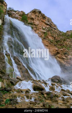 The image shows a powerful waterfall cascading down a rocky cliff. Stock Photo