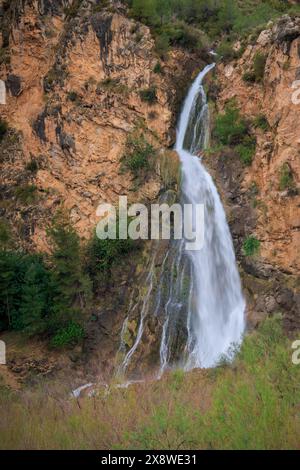 The image features a tall, cascading waterfall flowing down a rugged. Stock Photo