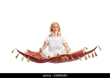 Middle aged woman in white clothes practicing yoga and sitting on a flying carpet isolated on white background Stock Photo