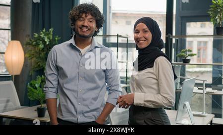 Two happy smile business partners diverse multiracial colleagues coworkers managers entrepreneurs Muslim islamic businesswoman in hijab Indian Stock Photo