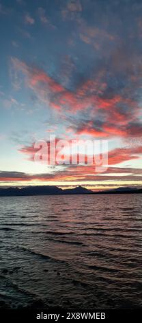 Beautiful sunset over a calm sea with vibrant pink and orange clouds reflecting on the water, creating a stunning landscape Stock Photo
