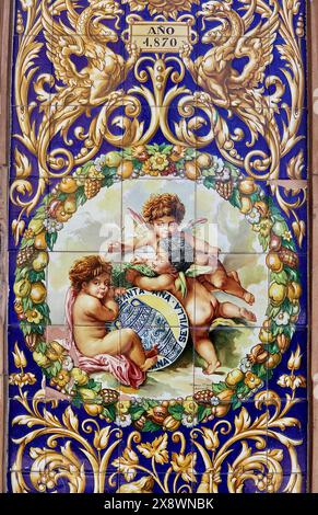 Ornate painted wall tiles, or azulejos, showing cherubs enjoying their visit to Seville, Spain Stock Photo