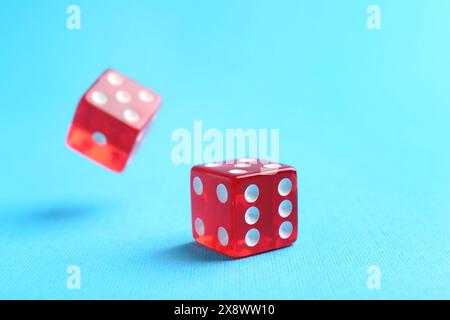 Two red game dices falling on light blue background, closeup Stock Photo