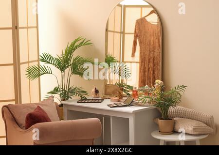 Dressing table with makeup products and palms in room Stock Photo