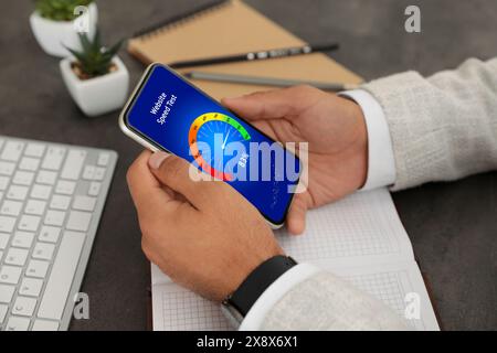Website speed test. Man using mobile phone at table, closeup Stock Photo