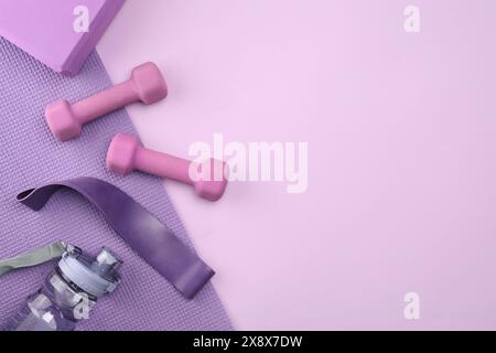 Two dumbbells, yoga block, mat and fitness elastic band on violet ...