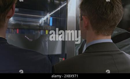 Team of start up businesspeople entering modern elevator and discussing corporate meeting. Stock clip. Businessmen using elevator to get to upper Stock Photo