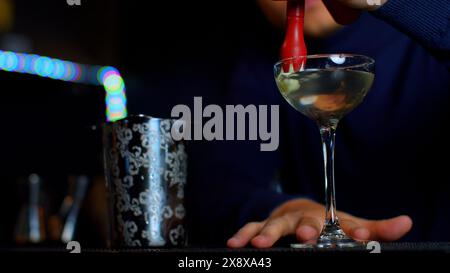 A professional bartender preparing an alcoholic cocktail with cream topping. Media. Making a beverage at the bar or disco club. Stock Photo