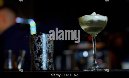 A professional bartender preparing an alcoholic cocktail with cream topping. Media. Making a beverage at the bar or disco club. Stock Photo