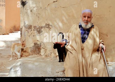 An old Mozabite man in traditional clothing with two cats in Ksar Beni Isguen.Beni Isguen is one of the 5 Ksars (fortified settlement) in Mzab valley.Ghardais Province.North Sahara.Algeria Stock Photo