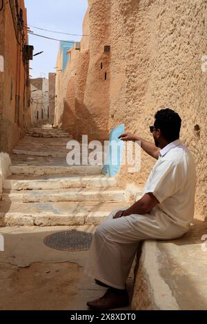 A man in a white robe looking at the traditional architectures in Ksar Beni Isguen Mzab valley.Ghardaia province.North Sahara.Algeria Stock Photo