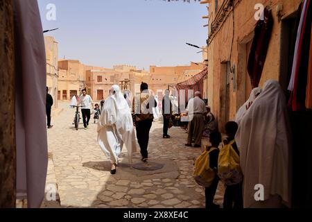 Veiled Mozabite women in white haik in market square of Ksar Beni Isguen.Beni Isguen is one of the 5 Ksars (fortified settlement) in Mzab valley.Ghardaia province.North Sahara.Algeria Stock Photo