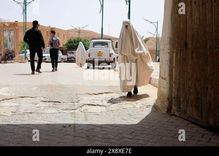 A veiled Mozabite women in white haik entering the gate of Ksar Beni Isguen.Beni Isguen is one of the 5 Ksars (fortified settlement) in Mzab valley.Ghardaia province.North Sahara.Algeria Stock Photo