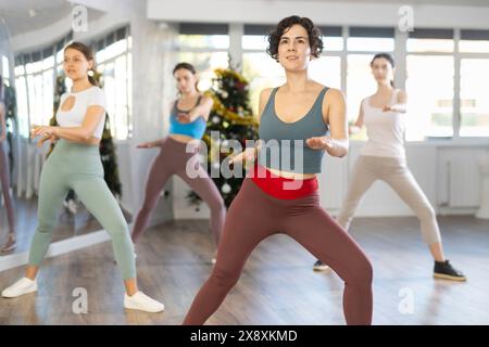 Enthusiastic Hispanic woman leading dance fitness class during Christmas season Stock Photo
