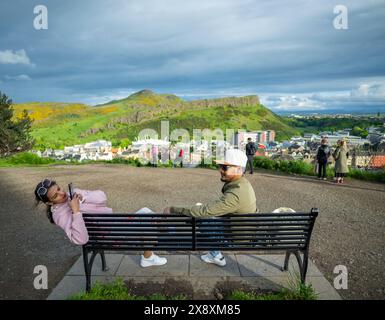 Edinburgh, UK. 27th May, 2024. UK Tourists take a photo on Carlton Hill. Edinburgh A view looking from Carlton Hill over towards Arthurs Seat, Scottish Parliament (bottom left) and Dynamic Earth (centre) Pic Credit: phil wilkinson/Alamy Live News Stock Photo