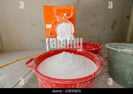 Electric mixer for mixes dry white putty, stir plaster and water in a several large buckets. Stock Photo