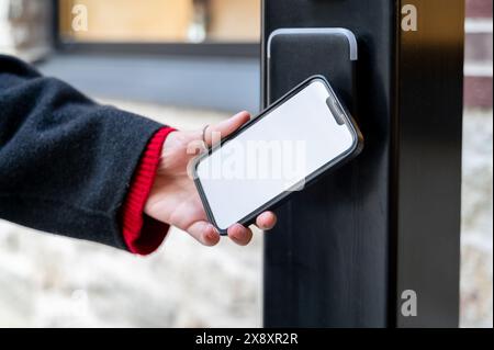 Hand holding smartphone opening door using smart digital lock. Integration of smart technology into everyday life Stock Photo