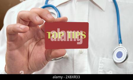 Business concept. Text TOP TIPS on a business card, a card in the hand of a man in a white shirt with a stethoscope around his neck Stock Photo